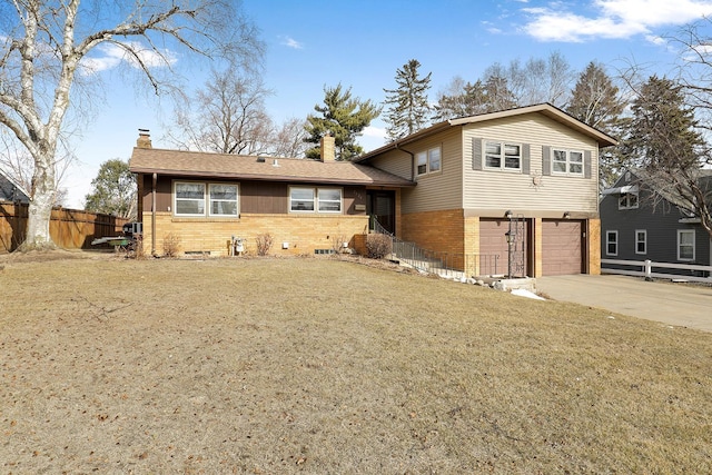 split level home featuring concrete driveway, fence, brick siding, and a chimney