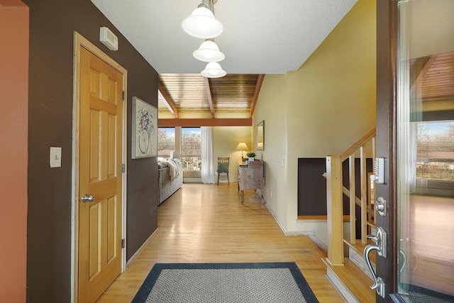 corridor with stairway, beamed ceiling, light wood-type flooring, and baseboards