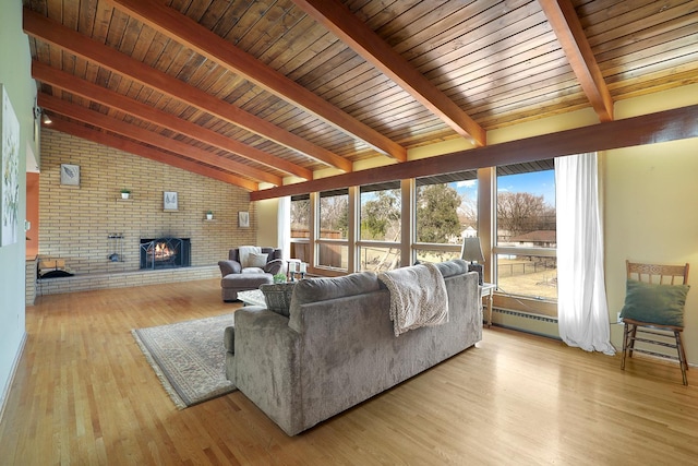 living room featuring light wood finished floors, brick wall, vaulted ceiling with beams, wood ceiling, and a brick fireplace