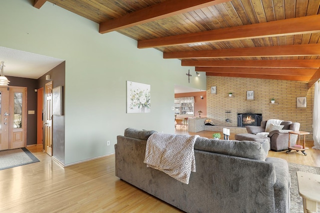 living room with light wood finished floors, a fireplace, vaulted ceiling with beams, and wood ceiling