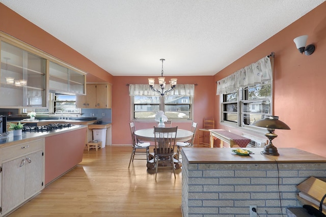 kitchen with light wood finished floors, stainless steel gas cooktop, decorative light fixtures, an inviting chandelier, and a textured ceiling