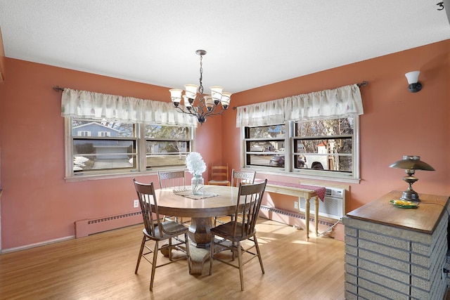 dining area featuring a baseboard heating unit, a chandelier, an AC wall unit, wood finished floors, and a textured ceiling