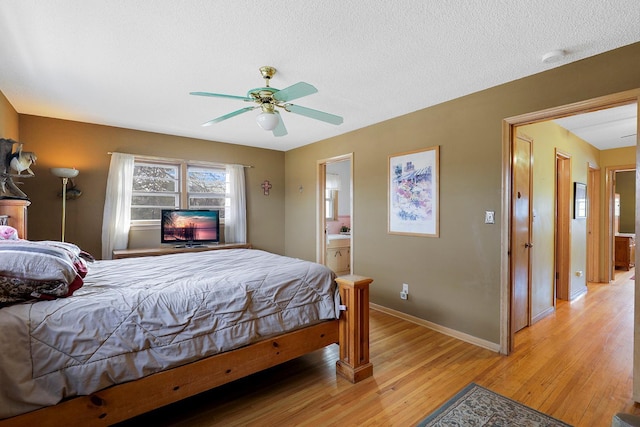 bedroom featuring connected bathroom, baseboards, light wood-type flooring, a textured ceiling, and a ceiling fan