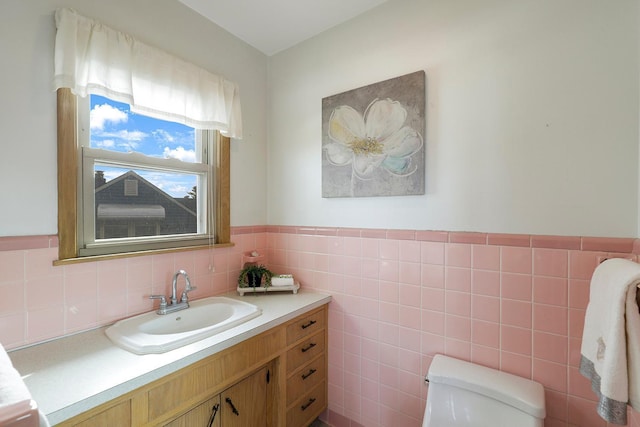 bathroom with vanity, tile walls, toilet, and a wainscoted wall