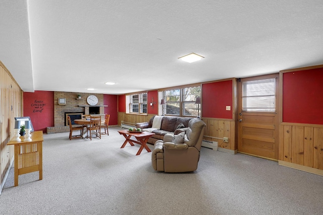 carpeted living area featuring baseboard heating, a brick fireplace, wooden walls, and a textured ceiling