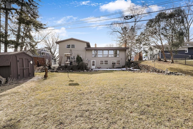 rear view of property featuring fence, a lawn, a chimney, an outbuilding, and a storage unit