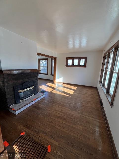 unfurnished living room with a brick fireplace and dark hardwood / wood-style floors