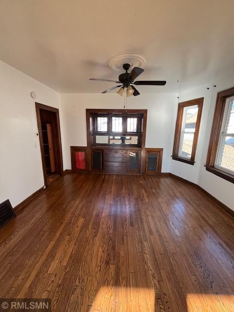 unfurnished living room featuring ceiling fan and dark hardwood / wood-style flooring