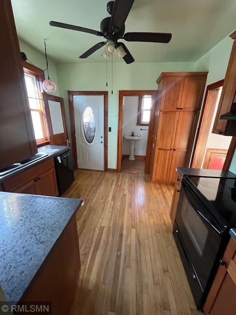 kitchen featuring pendant lighting, a wealth of natural light, black appliances, and light hardwood / wood-style floors