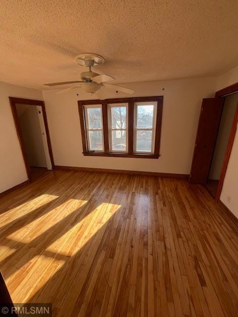 empty room with ceiling fan, light hardwood / wood-style floors, and a textured ceiling