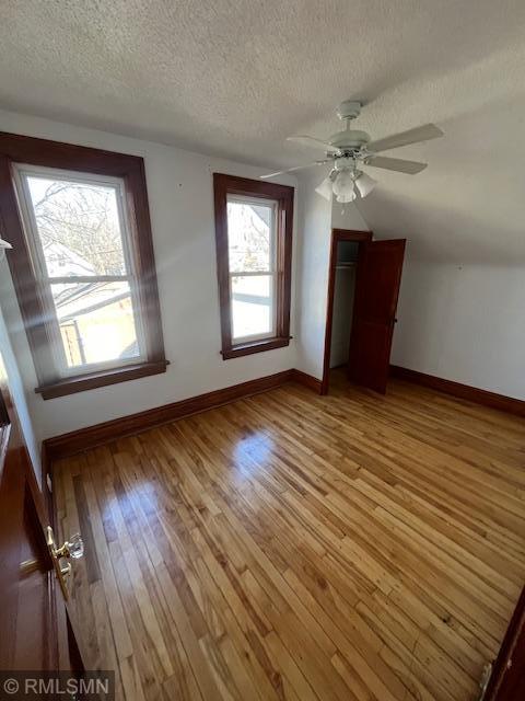 additional living space with ceiling fan, a textured ceiling, and light wood-type flooring