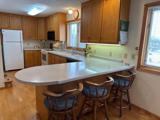 kitchen with white appliances, a kitchen breakfast bar, kitchen peninsula, and sink