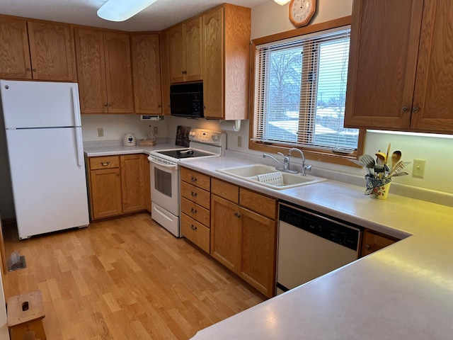 kitchen featuring white appliances, sink, and light wood-type flooring