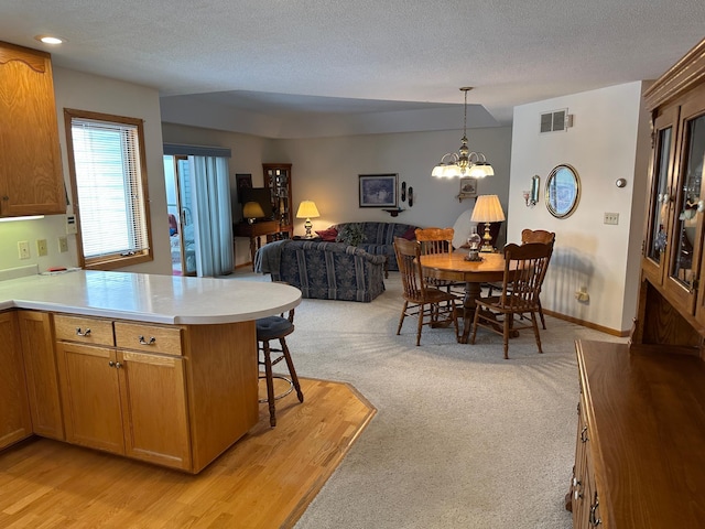 kitchen featuring pendant lighting, a kitchen breakfast bar, a notable chandelier, a textured ceiling, and kitchen peninsula