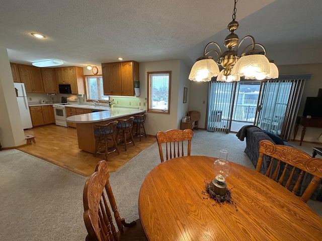 dining area featuring sink, light carpet, a notable chandelier, and a textured ceiling