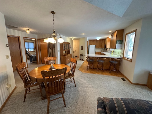 carpeted dining space featuring a chandelier, sink, and a textured ceiling