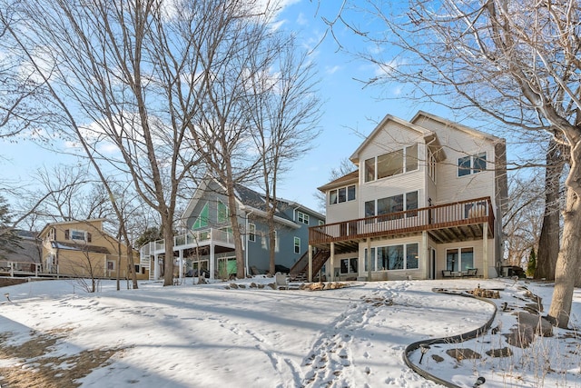 snow covered house featuring stairway and a wooden deck