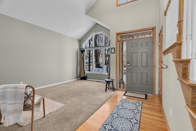 entrance foyer featuring high vaulted ceiling, light wood-style flooring, and baseboards