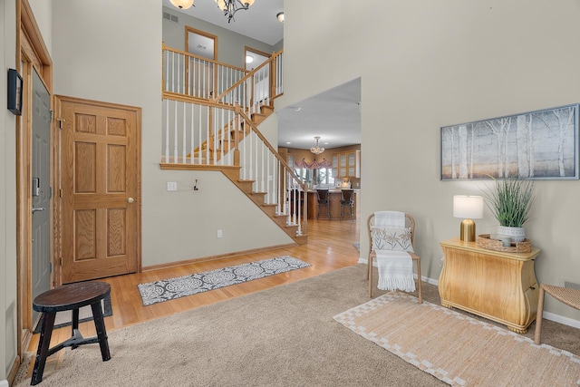 foyer with a towering ceiling, light wood finished floors, stairs, and a chandelier