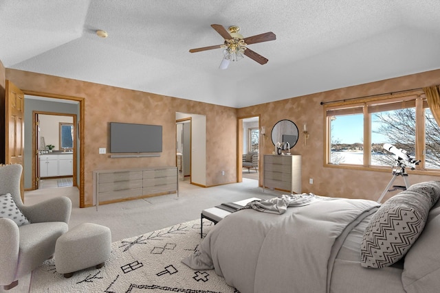 bedroom with ceiling fan, a textured ceiling, connected bathroom, light colored carpet, and vaulted ceiling