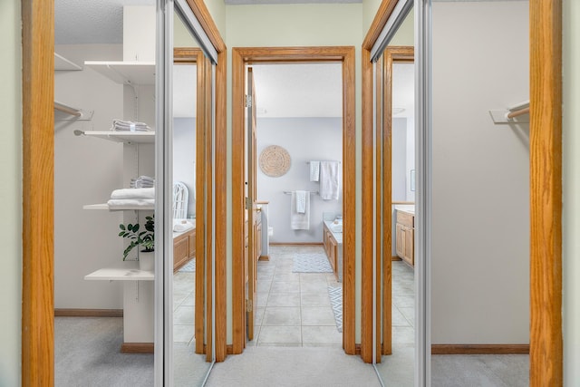 hall with baseboards and light tile patterned flooring