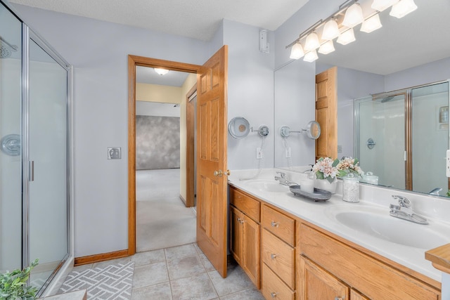 full bath featuring double vanity, a stall shower, a sink, and tile patterned floors