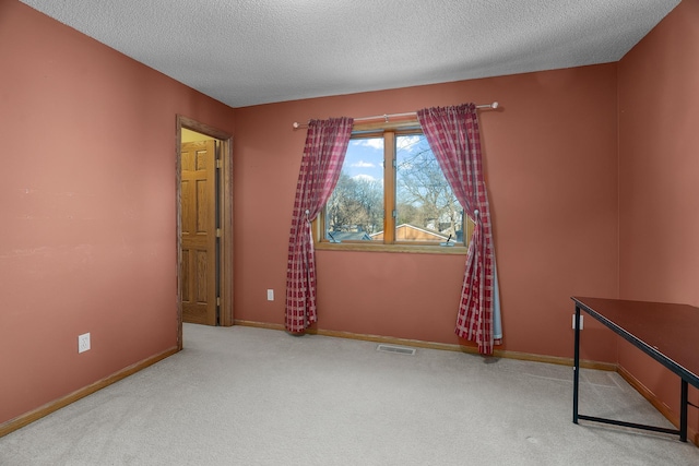 carpeted empty room with visible vents, a textured ceiling, and baseboards