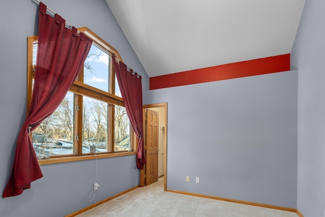 unfurnished room featuring a wealth of natural light, light colored carpet, visible vents, and lofted ceiling