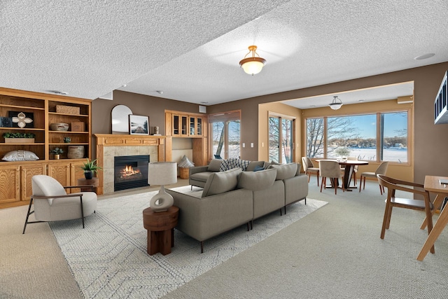 living room featuring light carpet, a healthy amount of sunlight, a fireplace, and a textured ceiling