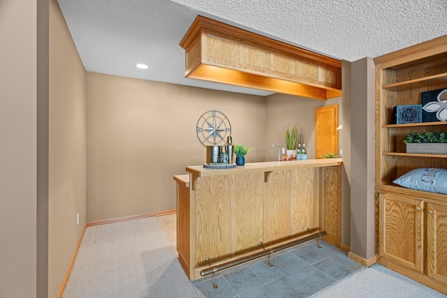 bar featuring light carpet, a sink, baseboards, and a textured ceiling