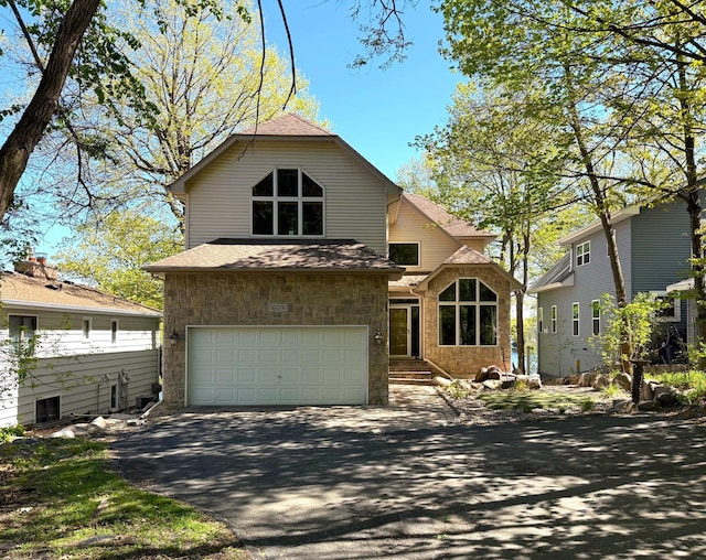 view of front of property featuring a garage, asphalt driveway, roof with shingles, and stone siding