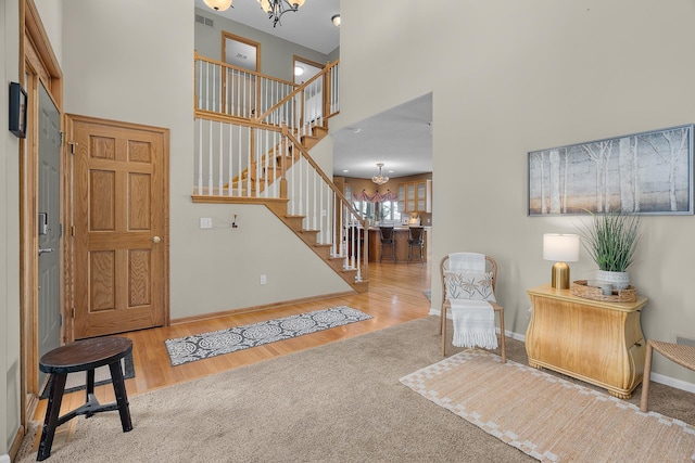 entrance foyer featuring a chandelier, stairs, a high ceiling, wood finished floors, and baseboards