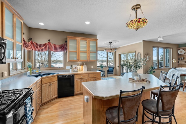 kitchen with black appliances, a sink, a textured ceiling, light countertops, and healthy amount of natural light
