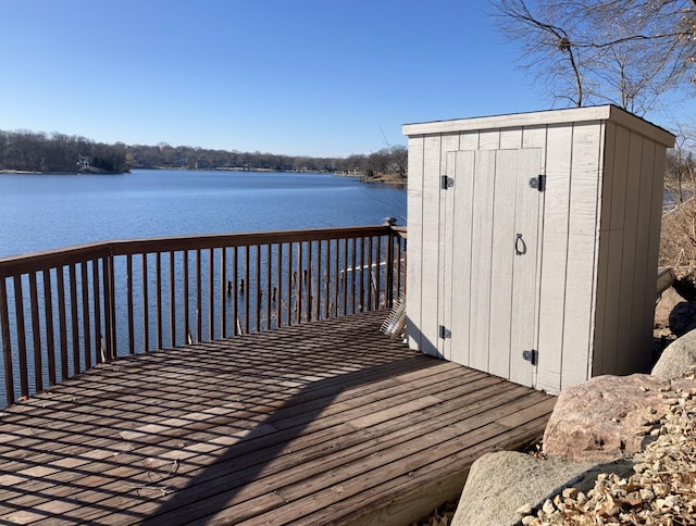 wooden terrace with a storage shed, a water view, and an outdoor structure