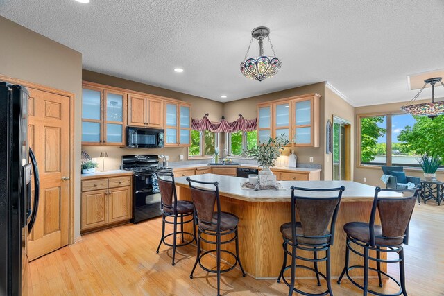 16091 Northwood Rd NW, Prior Lake, MN 55372 - kitchen with black appliances, light countertops, a kitchen bar, light wood-style flooring, and a textured ceiling