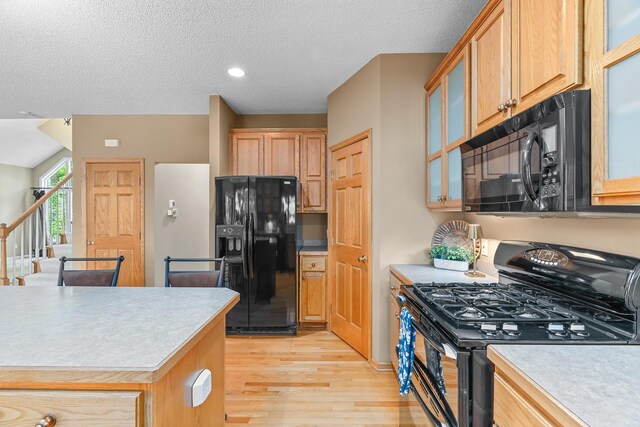 16091 Northwood Rd NW, Prior Lake, MN 55372 - kitchen with black appliances, light wood-type flooring, light countertops, a textured ceiling, and glass insert cabinets