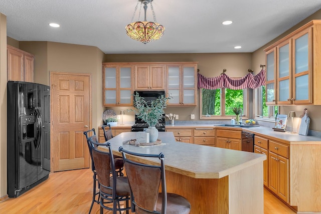 16091 Northwood Rd NW, Prior Lake, MN 55372 - kitchen with black appliances, a breakfast bar area, light wood finished floors, a kitchen island, and light countertops