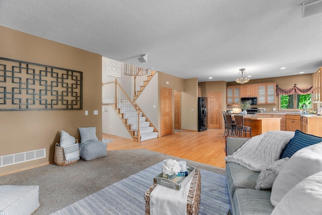 16091 Northwood Rd NW, Prior Lake, MN 55372 - living room featuring stairs, a textured ceiling, light wood finished floors, a chandelier, and recessed lighting