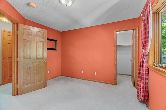 16091 Northwood Rd NW, Prior Lake, MN 55372 - unfurnished bedroom featuring a walk in closet, carpet flooring, a textured ceiling, and a closet