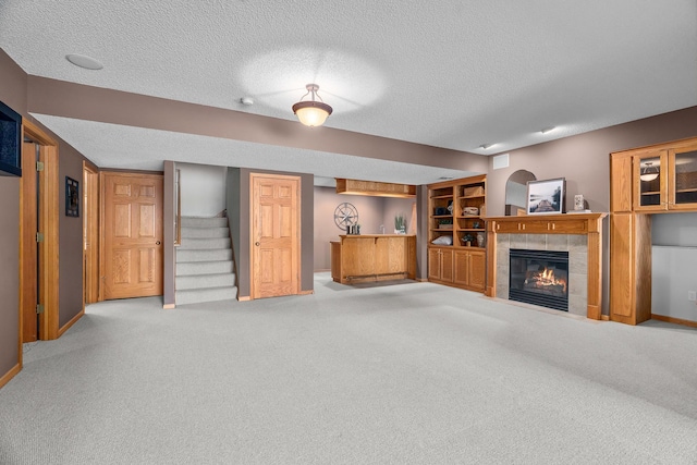 16091 Northwood Rd NW, Prior Lake, MN 55372 - unfurnished living room with a textured ceiling, carpet floors, a fireplace, and stairway