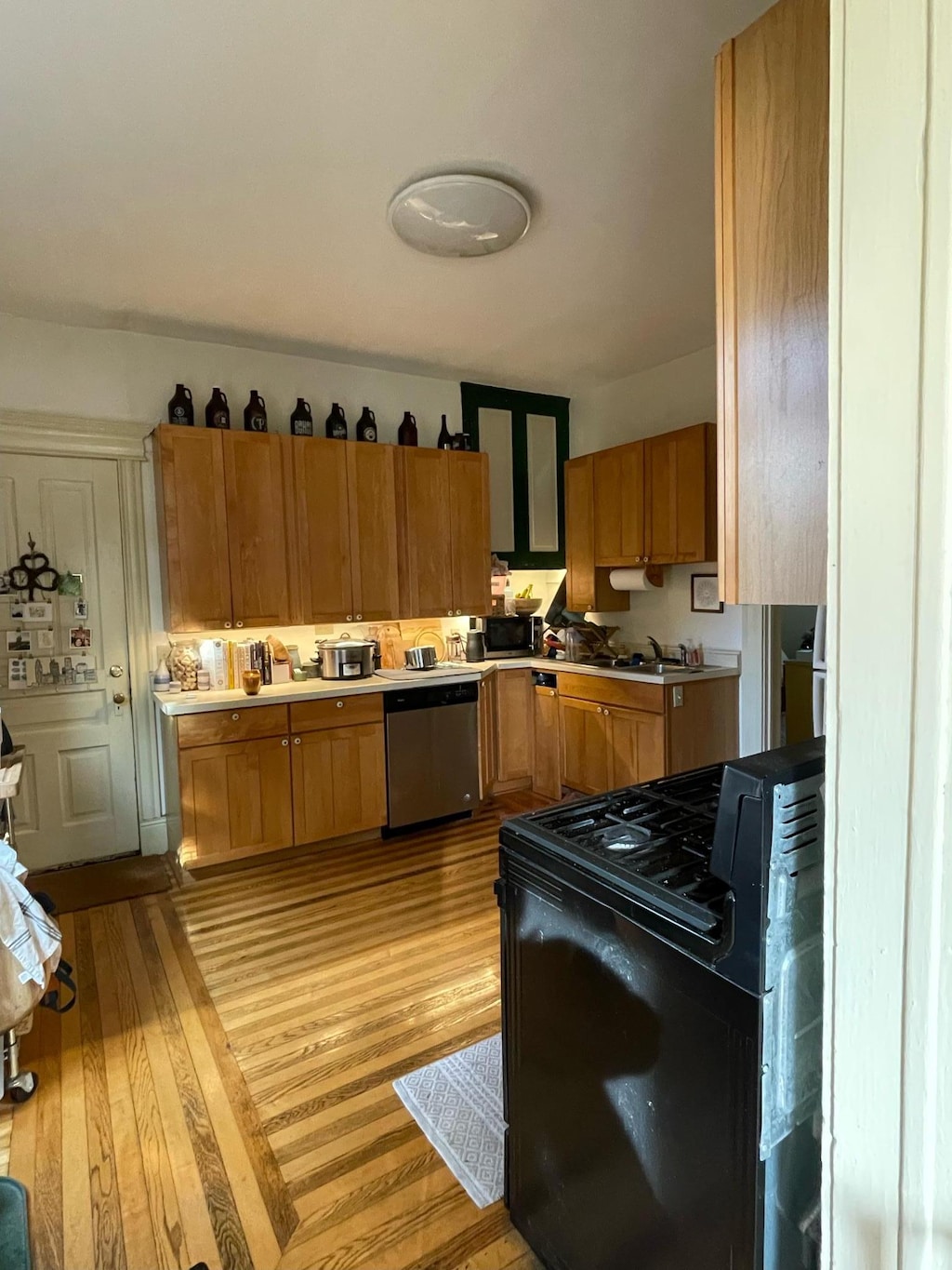 kitchen with light countertops, brown cabinetry, light wood-type flooring, and stainless steel appliances