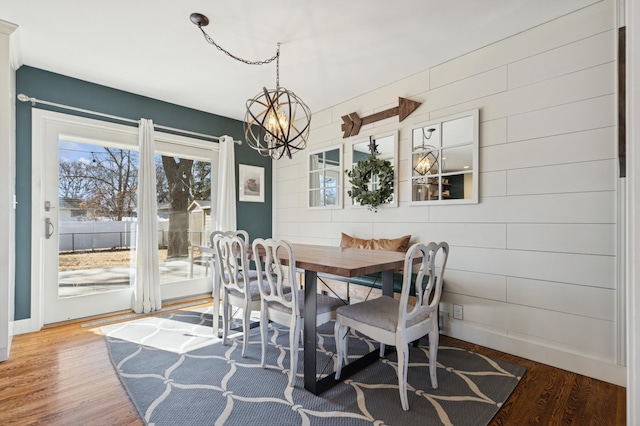 dining space with baseboards, an inviting chandelier, and wood finished floors