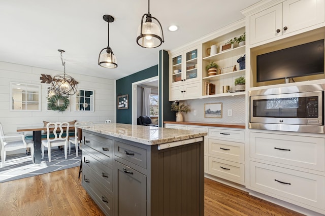 kitchen with gray cabinets, stainless steel microwave, white cabinets, and pendant lighting