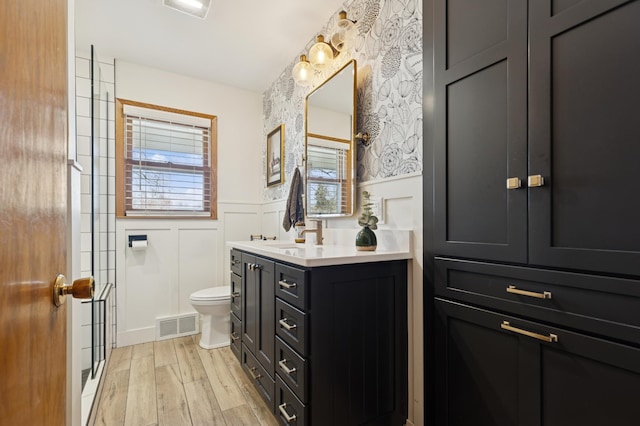 full bath featuring a healthy amount of sunlight, a wainscoted wall, visible vents, and wood finished floors