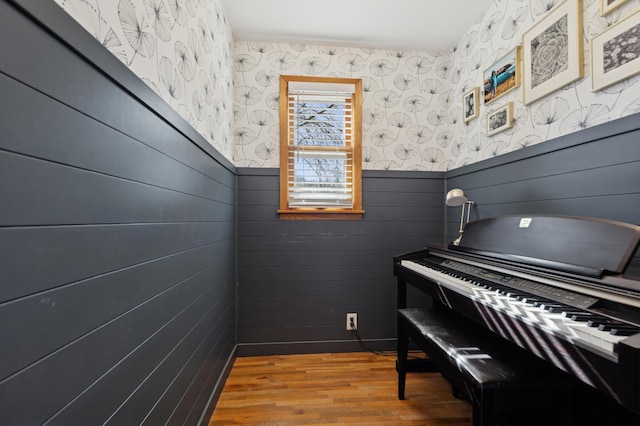 sitting room with wallpapered walls, wood finished floors, and wainscoting