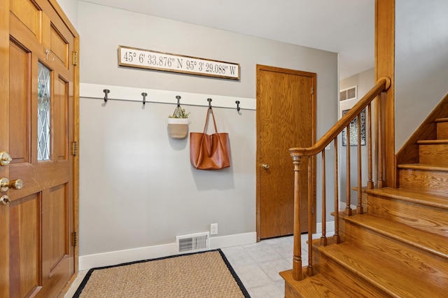 foyer with stairs, light tile patterned floors, visible vents, and baseboards