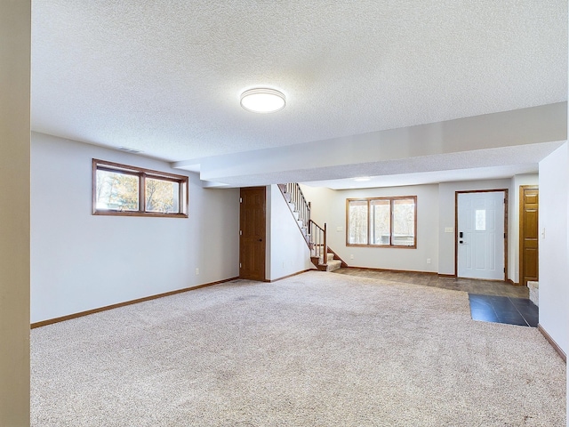 interior space featuring a wealth of natural light, a textured ceiling, and carpet flooring