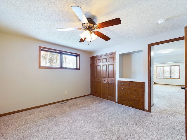 unfurnished bedroom with ceiling fan, carpet floors, a closet, and a textured ceiling