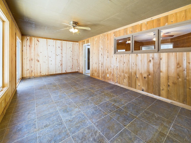 empty room with ceiling fan and wood walls