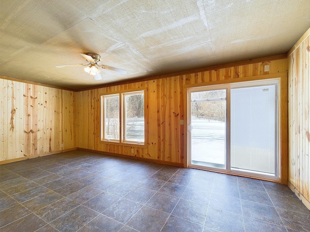 spare room featuring ceiling fan and wood walls